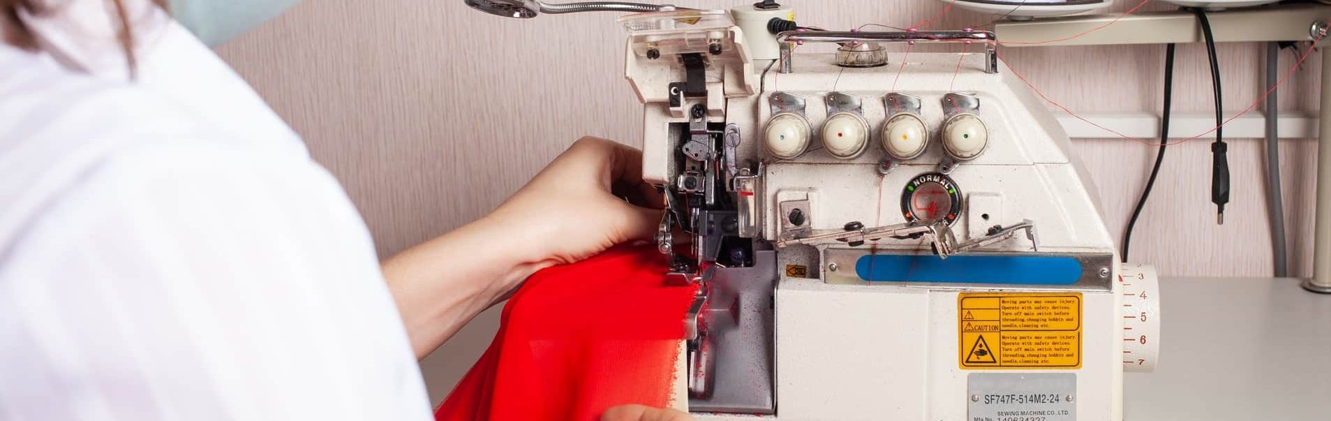 The seamstress in the mask overlays the edge of the fabric