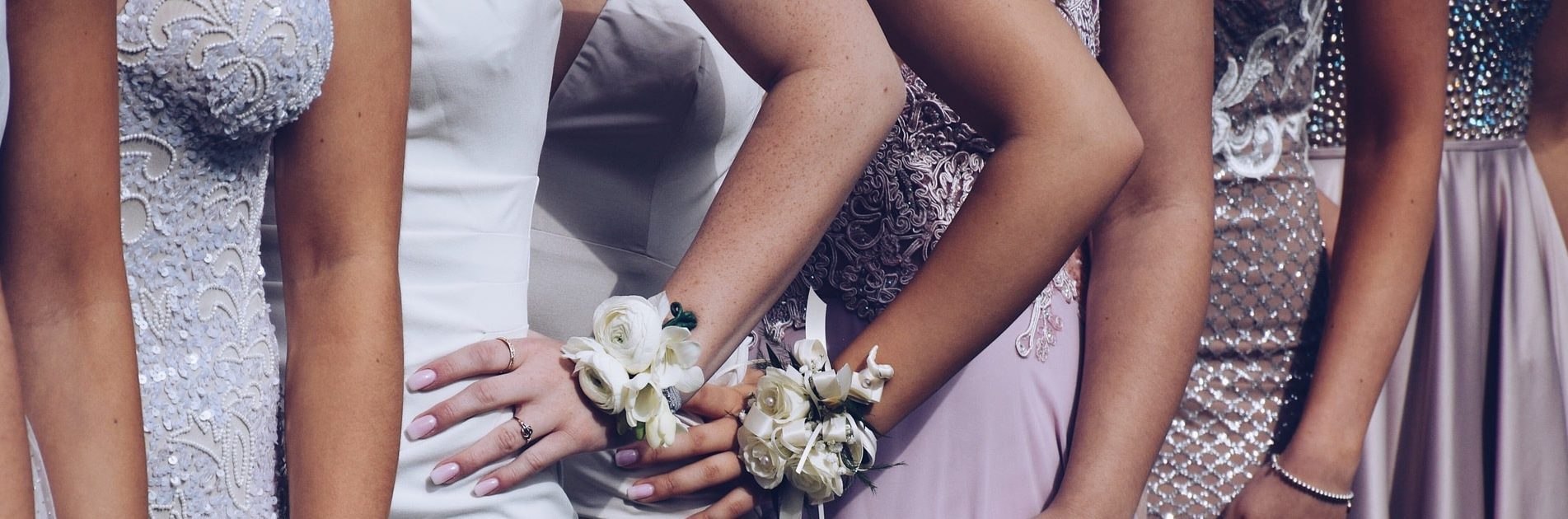 Young girls dressed in formal pastel colored gowns lined up for a picture wearing prom corsages